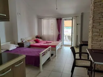 a bedroom with two beds and a table and a kitchen at 1-Bedroom Apartment in Bigovo