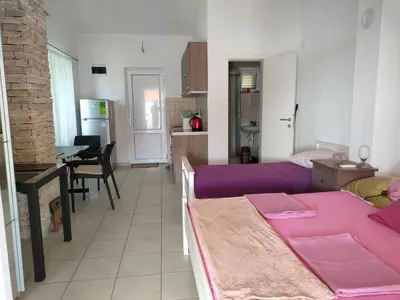 a living room with a purple couch and a kitchen at 1-Bedroom Apartment in Bigovo