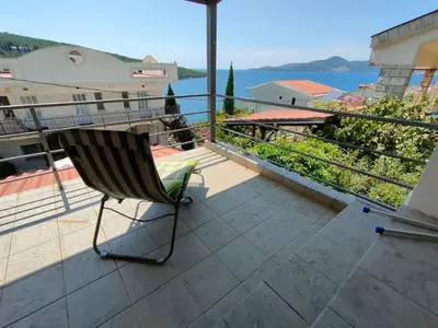 a chair on a balcony with a view of the water at 1-Bedroom Apartment in Bigovo