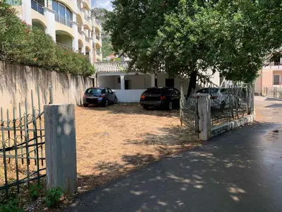 a fence with two cars parked next to a building at Apartment Danijela in Budva