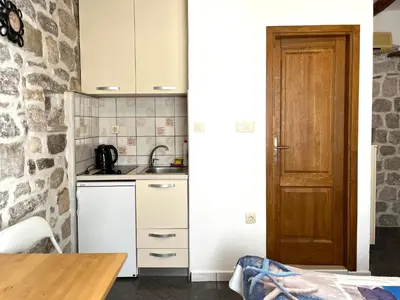 a kitchen with white cabinets and a wooden door at South Gate apartments 262 in Kotor