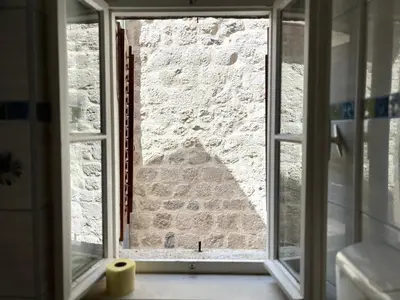 a window with a view of a stone wall at South Gate apartments 262 in Kotor