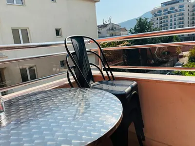 a table and chair on a balcony with a suitcase at Apartments MyDay in Budva