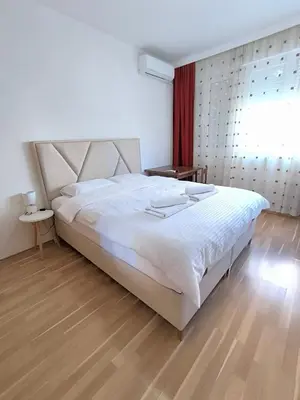 a bedroom with a large white bed and a window at Central Station Apartment Podgorica in Podgorica