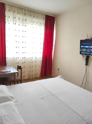 a bedroom with a bed and a window with red curtains at Central Station Apartment Podgorica in Podgorica