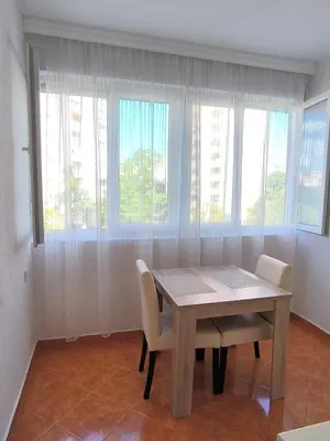 a dining room with a table and chairs and windows at Central Station Apartment Podgorica in Podgorica