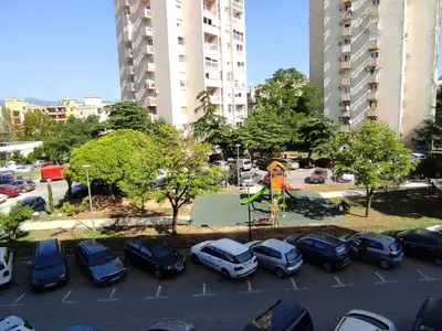 a parking lot with parked cars and a playground at Central Station Apartment Podgorica in Podgorica