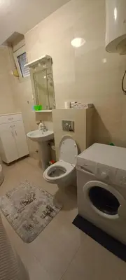 a bathroom with a toilet and a sink and a washing machine at Budva Morska oaza in Budva