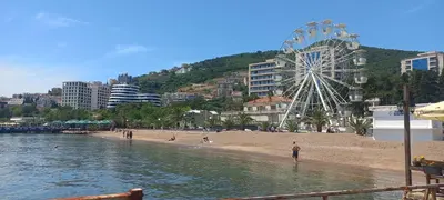 a beach with a ferris wheel in the background at Budva Morska oaza in Budva