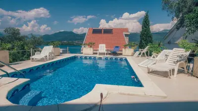 a swimming pool with chairs and a house at Villa Tivat in Tivat