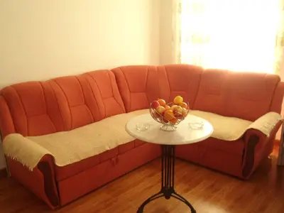 a red couch with a bowl of fruit on a table at Apartments Pekic in Bar