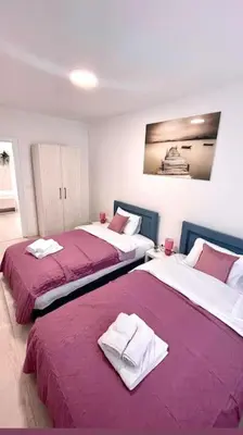 two beds in a room with purple sheets at Apartman DolceRosa in Kotor