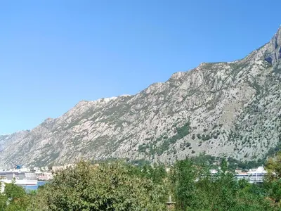 a mountain in the background with a city and trees at Apartman DolceRosa in Kotor