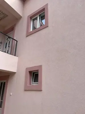 a pink building with three windows on the side of it at Apartman DolceRosa in Kotor