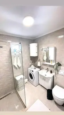 a bathroom with a toilet sink and a washing machine at Apartman DolceRosa in Kotor