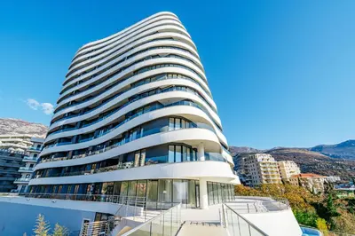 a tall white building with glass windows at Skyline Apartments by In Property in Becici