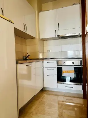 a kitchen with white cabinets and a stove at Urban Suite Athos in Podgorica