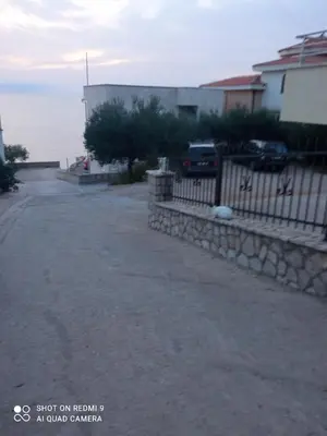 an empty street next to a house and the ocean at APARTMANI LUX SEA in Utjeha