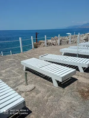 three white benches sitting next to the ocean at APARTMANI LUX SEA in Utjeha