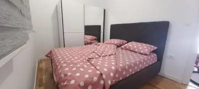 a bedroom with a bed with pink sheets and a mirror at RELAX in Podgorica