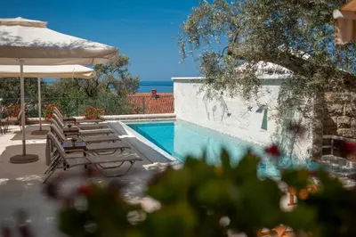 a swimming pool with lounge chairs and an umbrella at Villa Stevan in Sveti Stefan