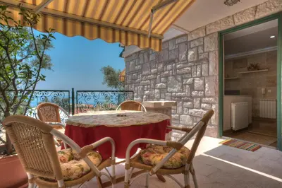 a table and chairs on a patio with a stone wall at Villa Stevan in Sveti Stefan