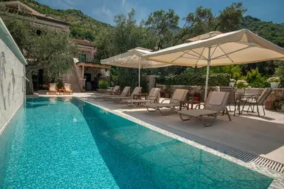 a swimming pool with chairs and an umbrella at Villa Stevan in Sveti Stefan