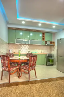 a kitchen with green cabinets and a table and chairs at Villa Stevan in Sveti Stefan