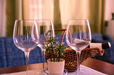 three wine glasses sitting on a table with a basket at Apartments Susanna in Ulcinj