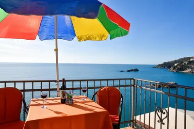 a table with a colorful umbrella on a balcony at Apartments Susanna in Ulcinj