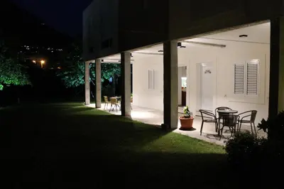 a patio with a table and chairs on a house at night at Apartments Grgurević in Kotor