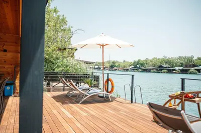 a wooden deck with chairs and an umbrella on the water at Congo Bungalow in Ulcinj