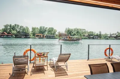 a deck with chairs and a table and a boat on the water at Congo Bungalow in Ulcinj