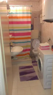 a bathroom with a rainbow shower curtain and a washing machine at Apartment Pela in Kotor