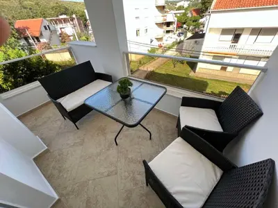 a balcony with a table and two chairs and a window at Apartments Pericic in Sutomore