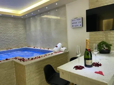 a hot tub with a table and a bottle of wine at Apartments Pericic in Sutomore