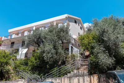 an apartment building with stairs in front of trees at Olive Garden Apartments in Sveti Stefan