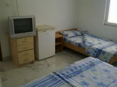 a bedroom with two beds and a tv on a dresser at Guest House Sandra in Kotor