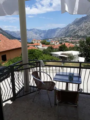 a balcony with a table and chairs and mountains at Guest House Sandra in Kotor