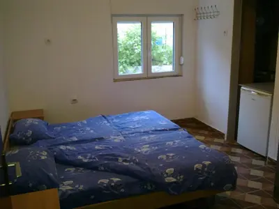 a bed with a blue comforter in a room with a window at Guest House Sandra in Kotor