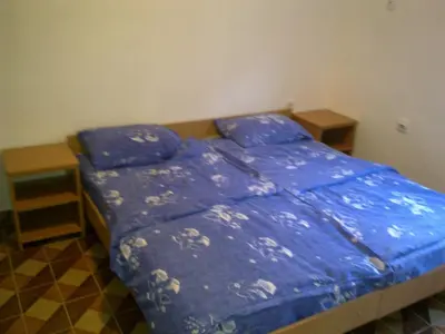 a bedroom with a bed with blue comforter and two tables at Guest House Sandra in Kotor