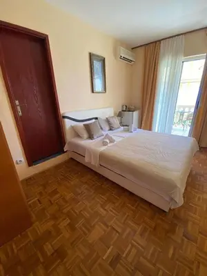 a bedroom with a large white bed with a wooden floor at Apartments Dunja in Sveti Stefan