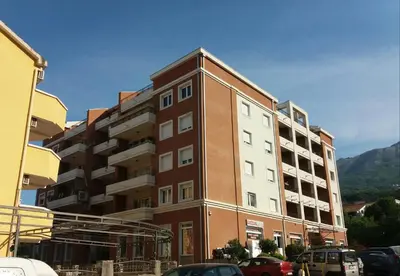 a tall building with cars parked in front of it at Apartment Marija in Budva