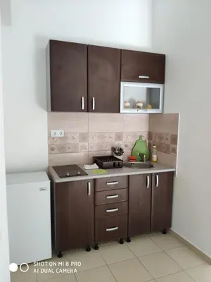 a kitchen with brown cabinets and a sink at Apartments Brnjada in Sutomore