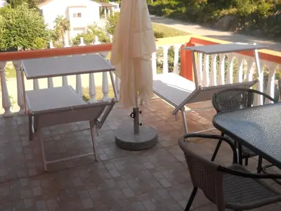 a patio with a table and an umbrella and chairs at Apartments Brnjada in Sutomore