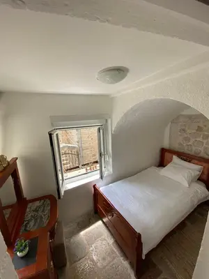 a small bedroom with a bed and a window at Apartment Ozana in Kotor