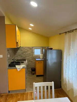 a kitchen with yellow walls and a stainless steel refrigerator at Prestige 3 in Podgorica