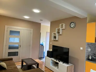 a living room with a television and a clock on a wall at Prestige 3 in Podgorica