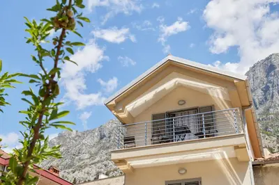 a building with a balcony with mountains in the background at Apartment Mrsulja in Kotor