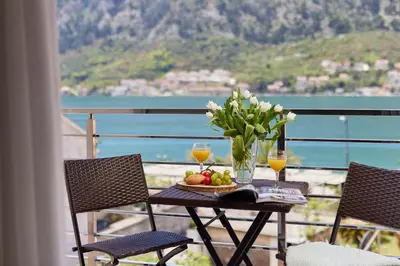 a table with a bowl of fruit and flowers on a balcony at Apartment Mrsulja in Kotor